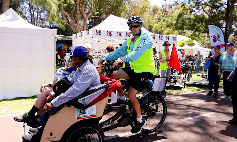 Image of volunteer cycling with carriage for older people