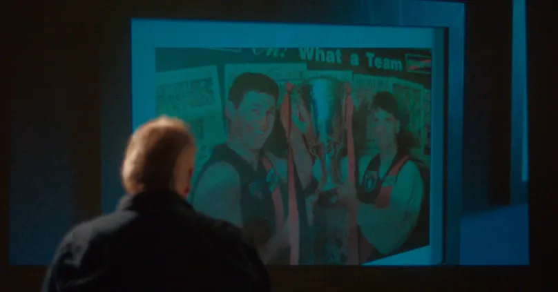 Barrie looking at his family on projector.