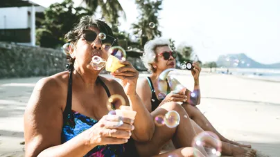 Two women blowing bubbles on a beautiful day at the beach.