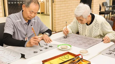 Image of older man and woman practising calligraphy.