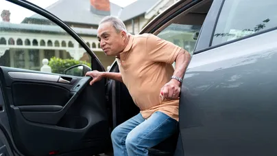 A man using a car assist bar to exit his car.