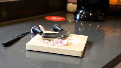 A two-handled herb chopper and its curved chopping board.