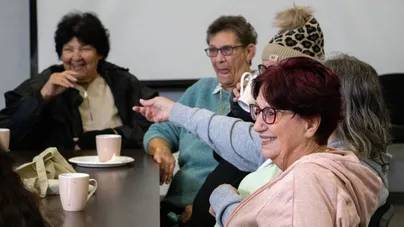 Women in a community sit around a table together for fun conversation.