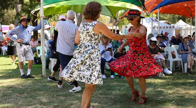 Image of two women in summer dresses dancing outside together