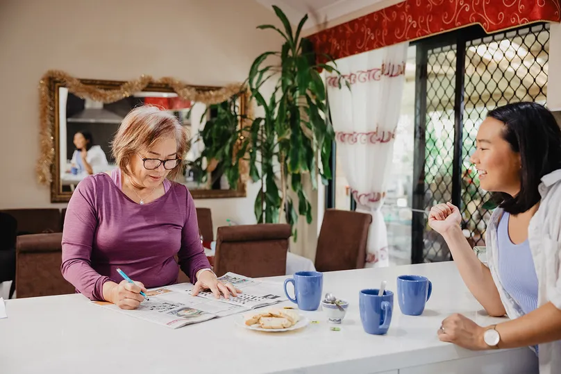 Image of a woman doing the crossword puzzle at home.