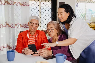 Image of a daughter showing her parents something on the smartphone.