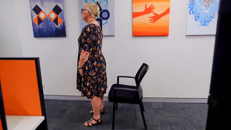 A woman standing in front of her chair.