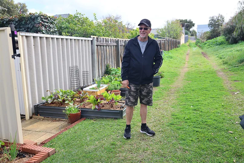Image of an older man standing by his veggie garden