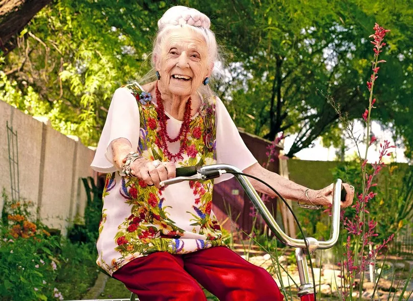 Image of Dr Gladys tricycling in her garden