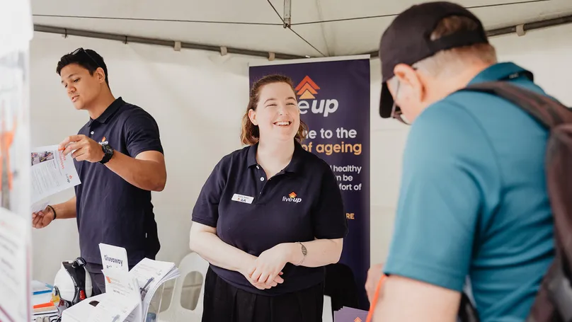 LiveUp team member at the have a go day stall talking to an older man. 