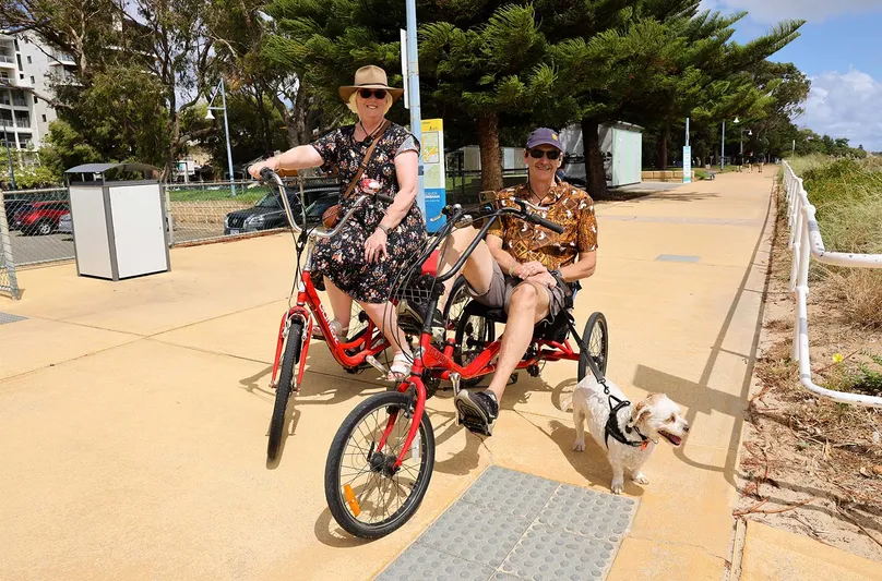 Ian and Gail cycling at the beach with dog.