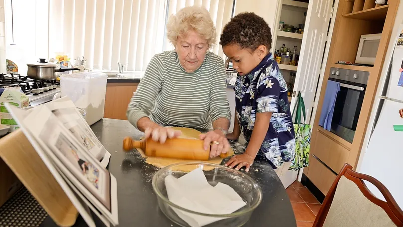 An older woman and her great grandson bake apple pie together