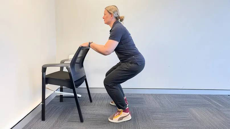 Image of woman doing knee bend with chair
