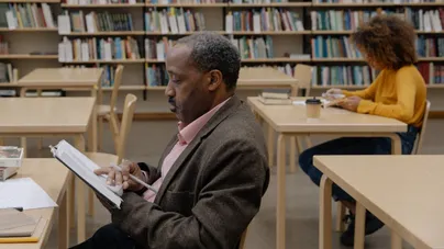 A man reading a book in a calm library.
