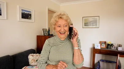 Image of an older woman laughing while talking on the phone