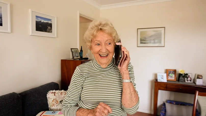 Image of an older woman laughing while talking on the phone