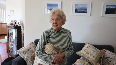 An older woman tidying up her quilting keepsakes.