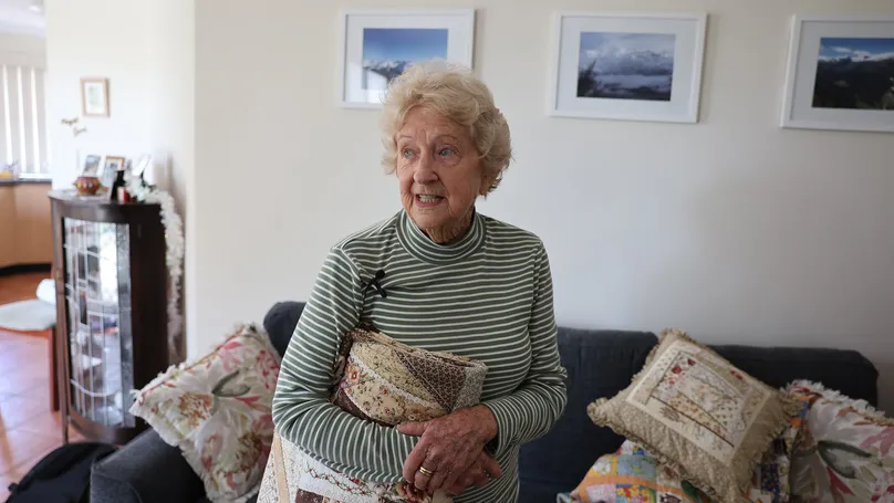An older woman tidying up her quilting keepsakes.