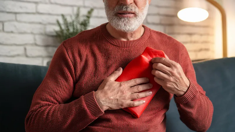 Man holding heat pack against his chest