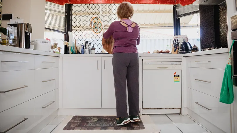 Myra standing on anti-fatigue mat while doing dishes in the kitchen.