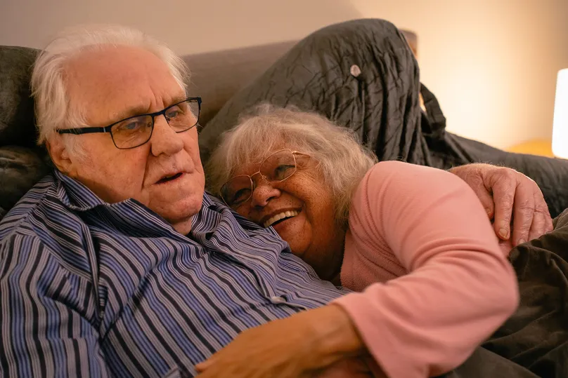 Image of an older couple cuddling in bed.