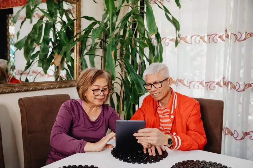 Older couple sitting at a table and using an iPad together.