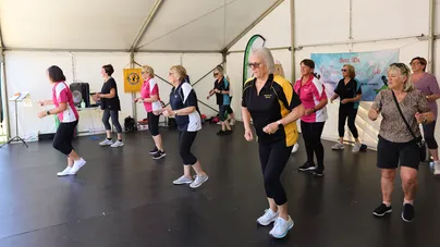 Image of a group of older ladies square dancing on a stage