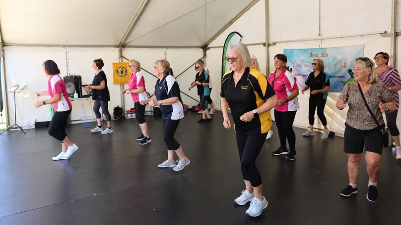 Image of a group of older ladies square dancing on a stage