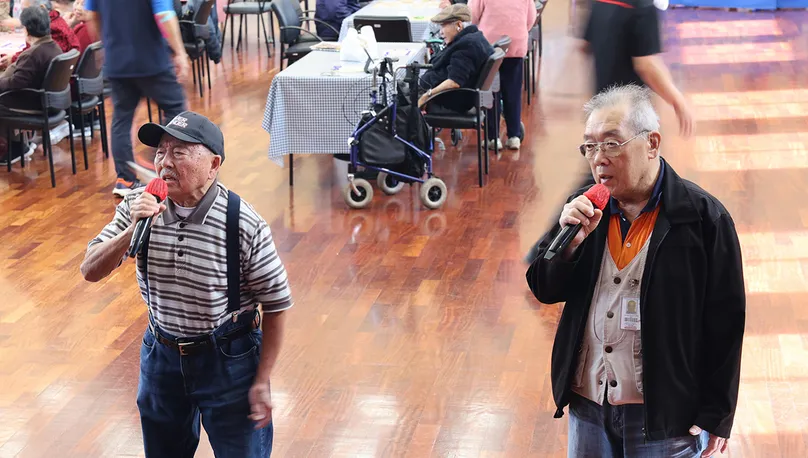 Two older men singing karaoke