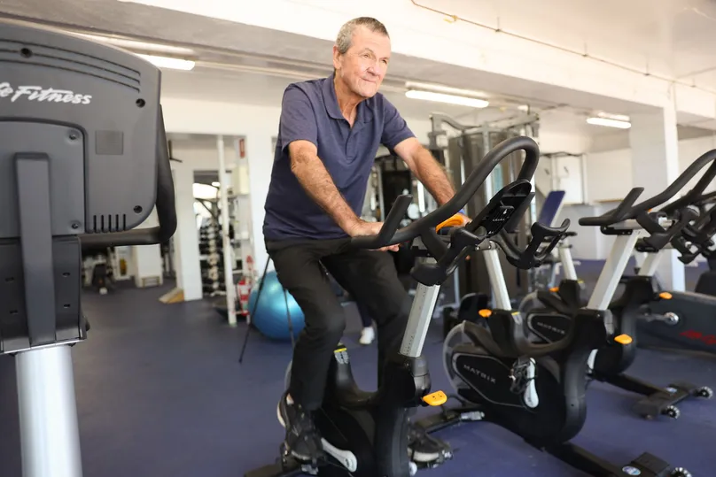 Image of an older man riding on a stationary bike at the gym.