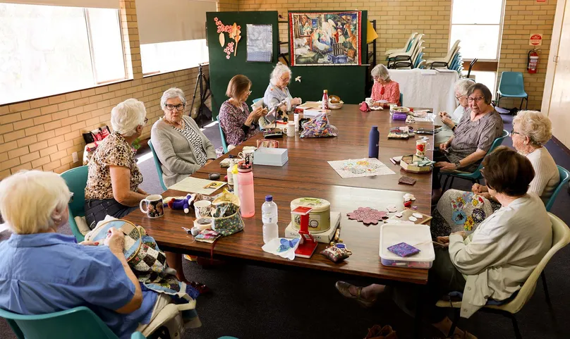 Women sitting around table quilting and talking.