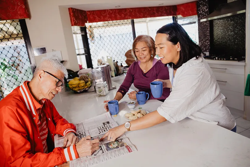 Image of a family in the kitchen reading the newspaper together.