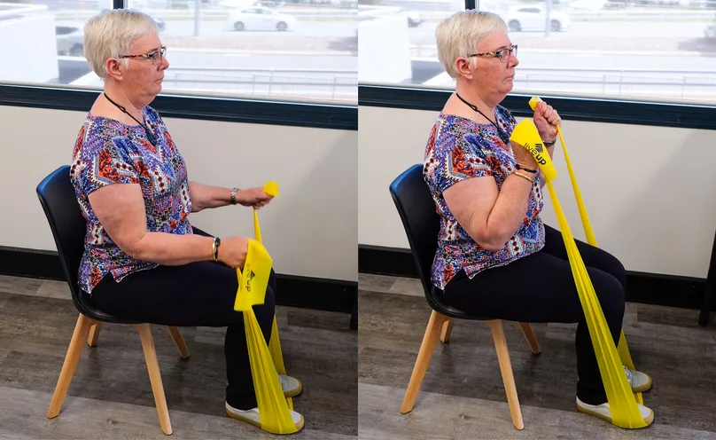 A woman doing a seated biceps curl with a resistance band.