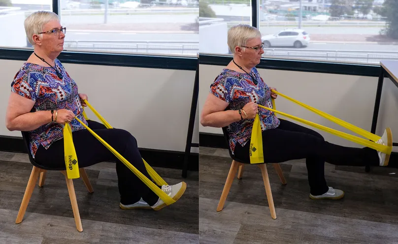 A woman doing a seated leg press exercise with a resistance band.