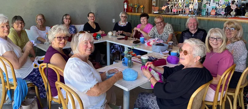 Women sitting in group in cafe smiling.