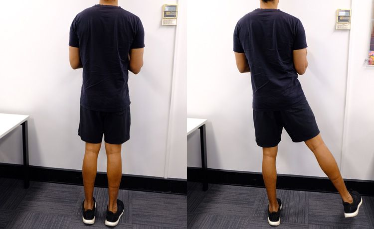 A man standing near a wall doing the side kick exercise.