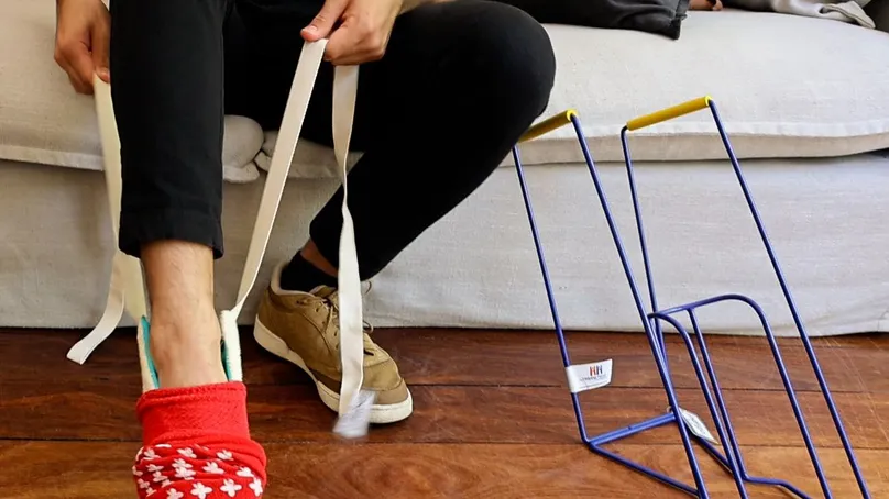 A man using a sock aid to put on his sock.