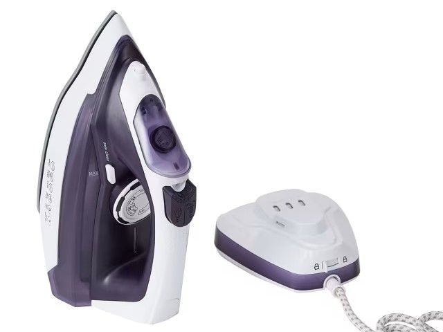 A cordless steam iron unclipped from its charging dock and standing independently.