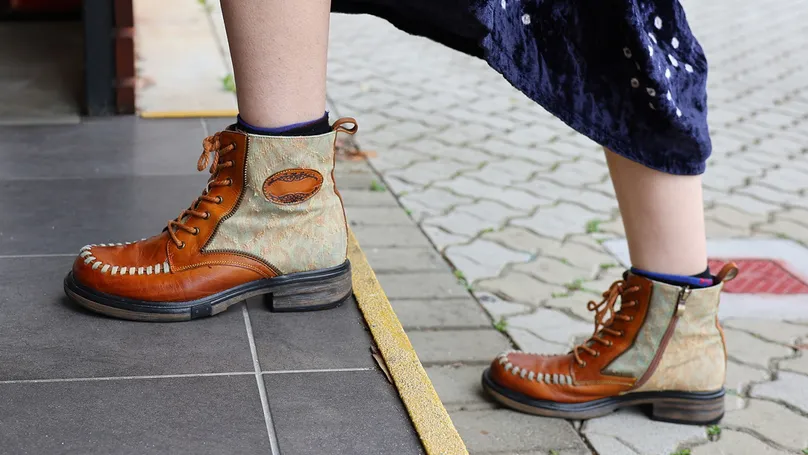 A woman's boots climbing an outdoor step.
