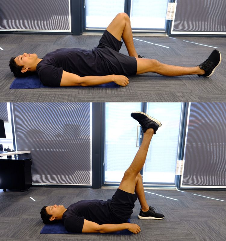 A man lying on the floor doing a straight leg raise.