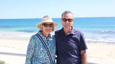 An older man and woman smiling at the beach.