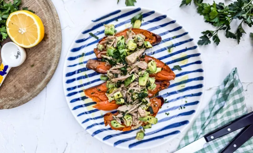 Roasted sweet potato adorned with tuna, avocado, and parsley