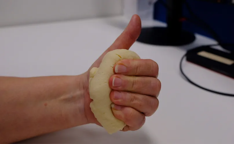 A hand making a hook fist with therapy dough.