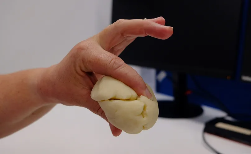 A hand doing the pinch exercise with therapy dough.