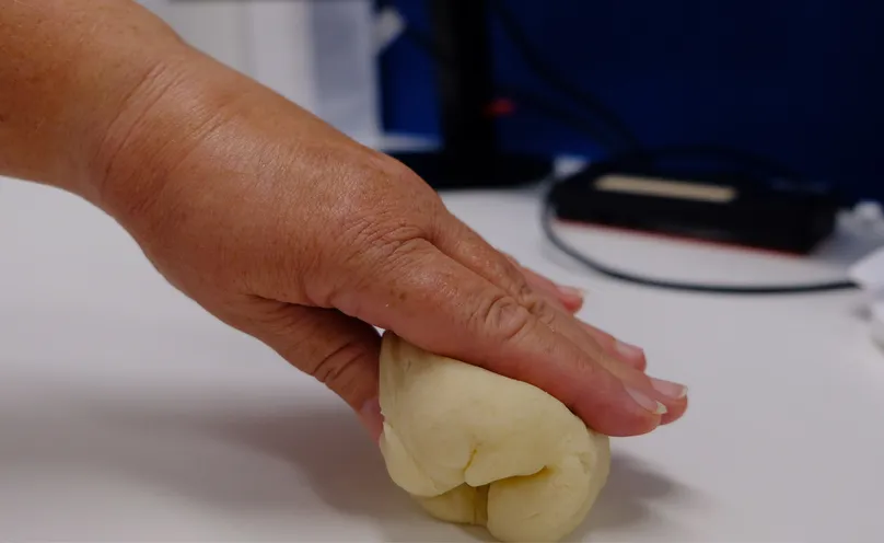 A hand doing a loose grip exercise with therapy dough.