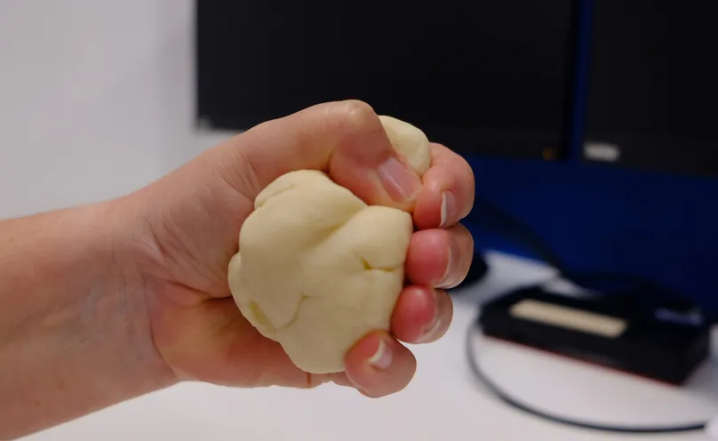 A hand making a fist with therapy dough.