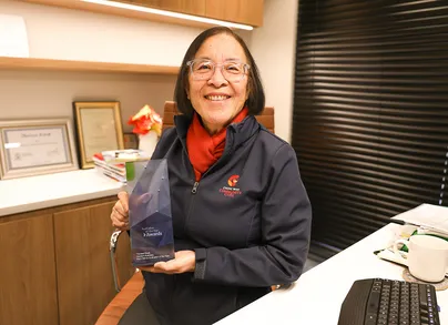 Theresa Kwok holding her award and smiling.