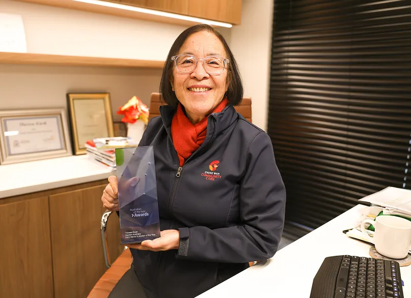 Theresa Kwok holding her award and smiling.