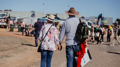 An older couple walking outside, holding hands.