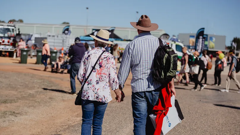 An older couple walking outside, holding hands.